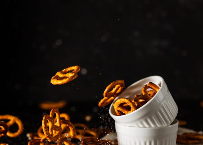 pretzels with salt fall from a white cup.